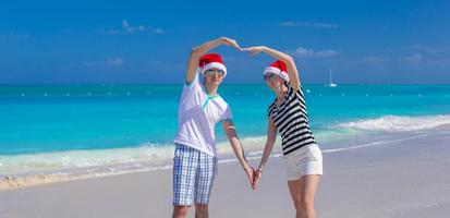 Porträt des jungen Paares in den Weihnachtsmützen genießen Strandurlaub foto