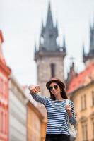 glückliche junge frau, die selfie-hintergrund berühmtes schloss in der europäischen stadt nimmt. kaukasischer tourist, der durch die menschenleeren straßen europas geht. warmer sommer am frühen morgen in prag, tschechische republik foto