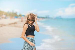 schönes jugendlich Mädchen, das die Kamera auf dem Strand betrachtet foto