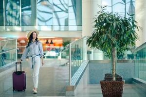 junge Frau mit Hut und Gepäck im internationalen Flughafen. foto