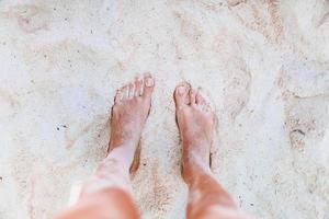 junge Frau, die am weißen Strand ein Sonnenbad nimmt. Beine. foto