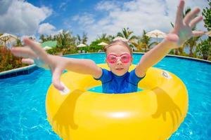 Porträt eines glücklichen Kindes mit aufblasbarem Gummikreis, das sich im Schwimmbad amüsiert foto