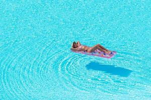 junge Frau im Bikini Luftmatratze im großen Swimmingpool foto