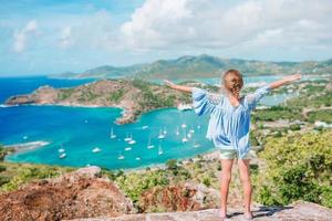 Entzückendes kleines Kind, das die Aussicht auf den malerischen englischen Hafen von Antigua in der Karibik genießt foto