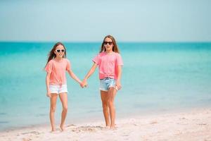 kleine glückliche lustige mädchen haben viel spaß am tropischen strand, der zusammen spielt. foto