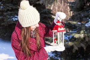 junge glückliche Frau mit roter Weihnachtslaterne im Schnee foto