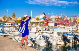 junge schöne Frau, die auf dem Dock in der Nähe des Bootes spazieren geht foto