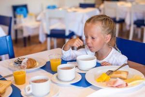 entzückendes kleines Mädchen, das im Restaurant frühstückt foto