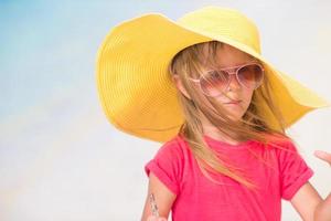 Entzückendes kleines Mädchen mit Hut am Strand während der Sommerferien foto