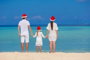 glückliche dreiköpfige Familie in Weihnachtsmützen am Strand foto