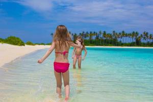 entzückende glückliche kleine mädchen haben spaß im seichten wasser im strandurlaub foto