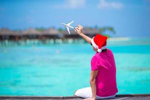 junger mann in weihnachtsmütze während des strandurlaubs auf holzsteg foto