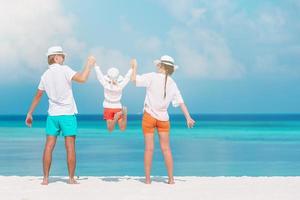 Glückliche dreiköpfige Familie, die gemeinsam Spaß am Strand hat foto