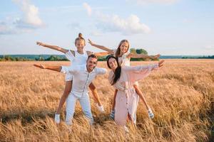 glückliche familie, die auf einem weizenfeld spielt foto