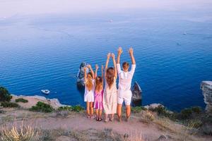 glückliche vierköpfige Familie, die bei Sonnenuntergang in den Bergen spazieren geht foto