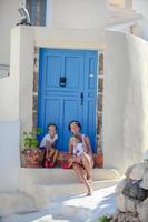 junge mutter und ihre tochter sitzen vor der haustür altes haus straße emporio, santorini foto