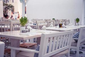 Weiße Tische mit Stühlen im leeren Open-Air-Café im Sommer foto