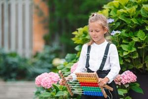 glückliches kleines Schulmädchen mit einer Tafel im Freien foto