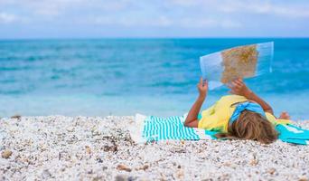 entzückendes kleines Mädchen mit Karte der Insel am tropischen Strand foto