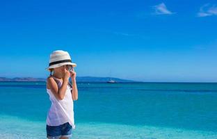 Kleines Mädchen, das sich am tropischen Strand mit weißem Sand und türkisfarbenem Meerwasser amüsiert foto