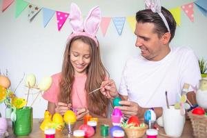 Vater und seine kleine Tochter malen Eier. glückliche familie, die sich auf ostern vorbereitet. foto