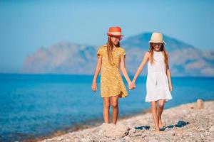 kleine glückliche lustige mädchen haben viel spaß am tropischen strand, der zusammen spielt foto