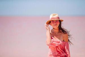 Frau mit Hut geht an einem sonnigen Sommertag auf einem rosafarbenen Salzsee spazieren. foto