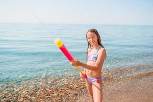 Entzückendes aktives kleines Mädchen am Strand während der Sommerferien foto