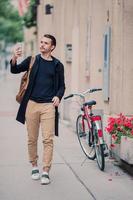 mann tourist mit stadtplan und rucksack in der europastraße. kaukasischer junge, der mit karte der europäischen stadt schaut. foto