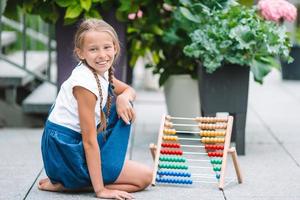 glückliches kleines Schulmädchen mit einer Tafel im Freien foto