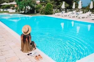 Frau, die sich am Pool in einem Luxushotelresort entspannt und einen perfekten Strandurlaub genießt foto