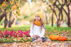 Kleines entzückendes Mädchen mit Kürbis im Freien an einem warmen Herbsttag. foto