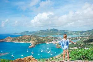 Entzückendes kleines Kind, das die Aussicht auf den malerischen englischen Hafen von Antigua in der Karibik genießt foto