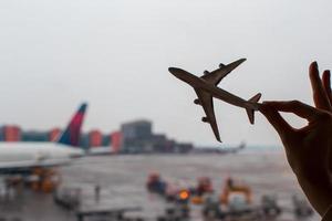 Nahaufnahmehand, die ein Flugzeugmodell am Flughafen hält foto