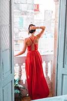 junge attraktive frau im roten kleid auf altem balkon in wohnung in havanna foto
