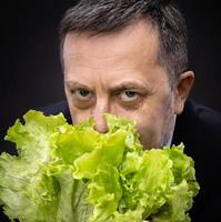 Mann, der Salat hält und isst foto