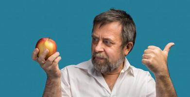 Mann mittleren Alters, der einen roten Apfel hält foto