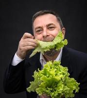 Mann, der Salat hält und isst foto