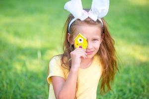 Entzückendes kleines Mädchen mit Hasenohren spielt mit Ostereiern foto