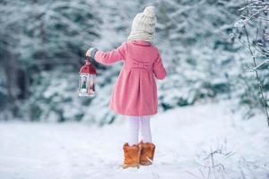 entzückendes kleines mädchen mit taschenlampe und kerze im winter foto