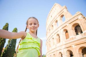 kleines mädchen, das selfie hintergrund macht kolosseum, rom, italien. Kinderporträt an berühmten Orten in Europa foto