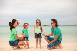 vierköpfige Familie am Meer spazieren und Strandurlaub genießen foto