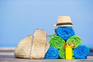 Zubehörkonzept für Strand- und Sommerferien - Nahaufnahme von bunten Handtüchern, Hut, Tasche und Sonnencreme foto