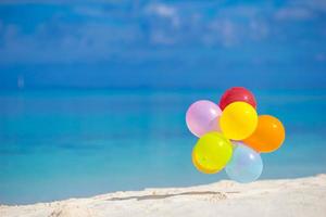 mehrfarbige Luftballons am weißen tropischen Strand foto