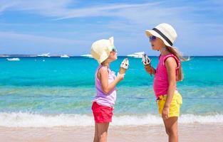 Kleine entzückende Mädchen, die Eis am tropischen Strand essen foto