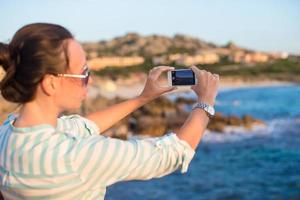 junge Frau macht während des Strandurlaubs ein Foto am Telefon