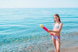 Entzückendes aktives kleines Mädchen am Strand während der Sommerferien foto