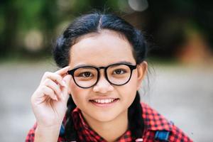 Porträt eines jungen Mädchens, das Brille hält und Kamera betrachtet foto