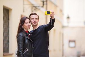 junges paar, das im urlaub in europa reist, lächelt glücklich. kaukasische familie, die selfie in europäischen leeren alten straßen macht foto