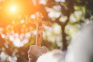 Hände halten ein Holzkreuz über dem Himmel foto